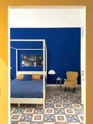 a bedroom with blue walls and a bed and a chair at B&B Palazzo Corselli in Bagheria