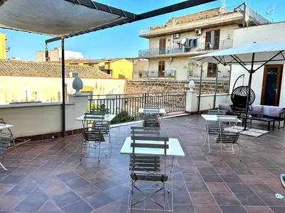 a patio with tables and chairs and an umbrella at B&B Palazzo Corselli in Bagheria