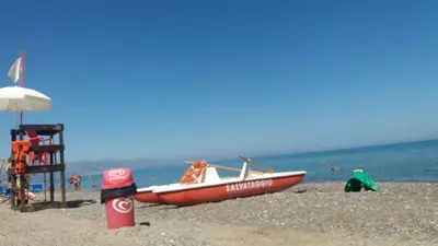 a red boat on the beach with a lifeguard chair at Beb oasi marina in Campofelice di Roccella