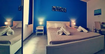 two pictures of a bedroom with a blue wall at A un passo dal centro in Palermo