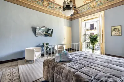 a bedroom with a large bed and a chair at SUITE S.LUCIA in Corleone