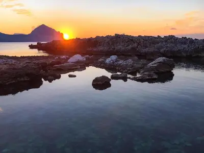 a sunset over a body of water with rocks at Casa Mandarino in Macari
