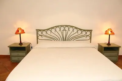 a bedroom with a white bed with two lamps on tables at Villa Porto Rais in Carini