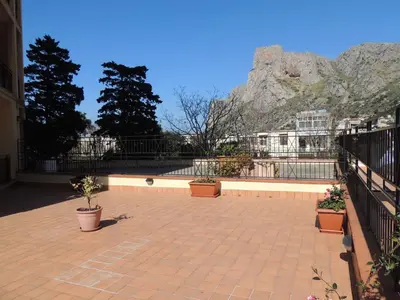 a patio with potted plants and a mountain in the background at La Locanda del Cedro in Palermo