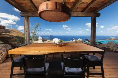 a wooden table on a patio with a view of the ocean at Casa Saleiman in Castellammare del Golfo