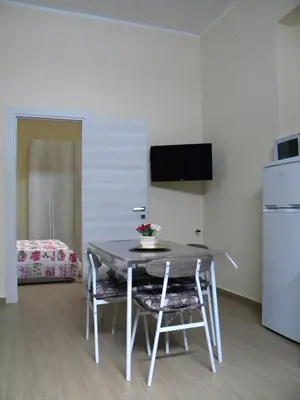 a dining room table with two chairs and a refrigerator at La Casetta del Viale 13 in Palermo