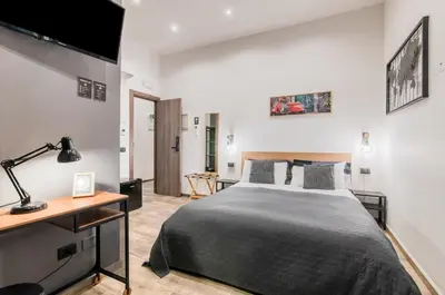 a bedroom with a bed and a desk and a television at Panurban Rooms by Wonderful Italy in Palermo