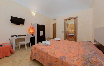 a bedroom with a bed and a desk and a television at Angolo Arancio Bed & Breakfast in San Vito lo Capo