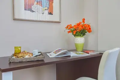 a desk with a vase of orange flowers and a book at Sturzo 44 in Palermo