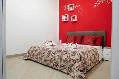 a bedroom with a bed with a red wall at BENVENUTI AL SUD in Castellammare del Golfo