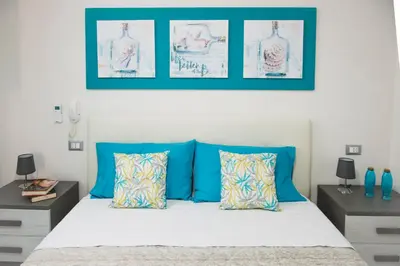 a bedroom with a bed with blue pillows and framed pictures at BENVENUTI AL SUD in Castellammare del Golfo