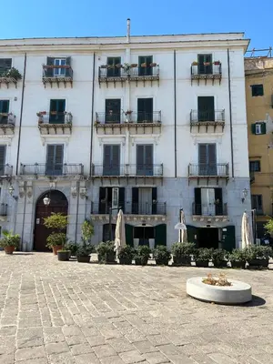 a large white building with umbrellas in front of it at Kalamarina Rooms in Palermo