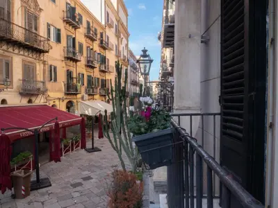 a city street with a balcony with flowers in a pot at Kalamarina Rooms in Palermo