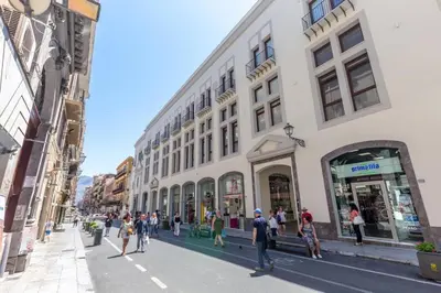 a group of people walking down a street next to a building at Solemar Sicilia - Galleria Maqueda in Palermo