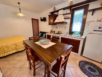 a kitchen and dining room with a wooden table and chairs at Monolocale da Mariolina in Macari