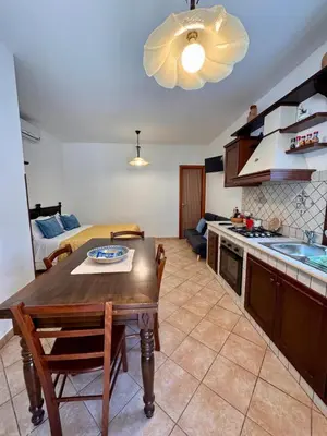 a kitchen and living room with a table and a couch at Monolocale da Mariolina in Macari