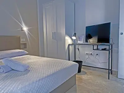 a bedroom with a bed and a desk with a television at Leone Suite B&B & Restaurant AIC in Palermo