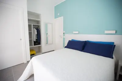 a white bed with blue pillows in a bedroom at White Asses Rooms in Castellammare del Golfo