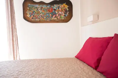 a painting hanging on a wall next to a bed at White Asses Rooms in Castellammare del Golfo