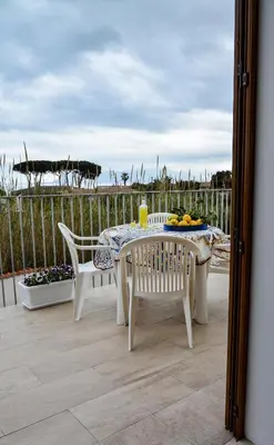 a table and chairs on a patio with a view of the ocean at Casa Pomelia in Castellammare del Golfo