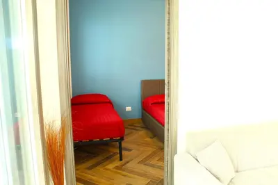 a mirror in a room with a red chair and a couch at Suite Capaci in Capaci