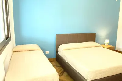 a bedroom with two beds and a blue wall at Suite Capaci in Capaci