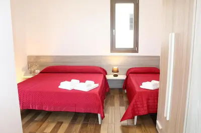 a room with two beds with red sheets and a window at Suite Capaci in Capaci