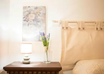 a vase of flowers on a table next to a bed at La casetta in Terrasini