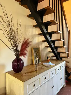 a wooden cabinet with a vase on top of it with a staircase at Mau House 44 Apartment in Palermo
