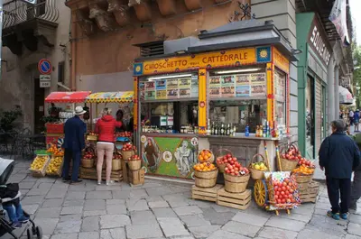 people standing around a food stand on a street at CATHEDRAL APARTMENT in Palermo