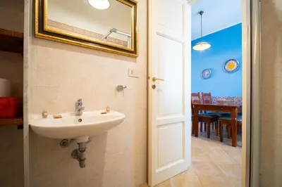 a bathroom with a sink and a dining room at Solemar Sicilia - Casa Enza in Santa Flavia