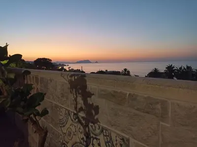 a sunset over the ocean and a stone wall at Torre Vallelunga in Trabia