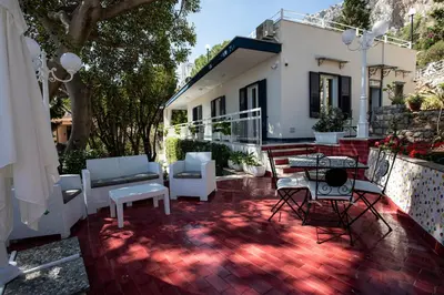 a patio with white chairs and tables and a house at Villa Aurora Mondello Addaura in Mondello