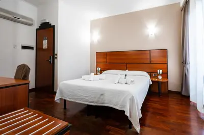 a bedroom with a large white bed with a wooden headboard at Hotel City Center in Palermo