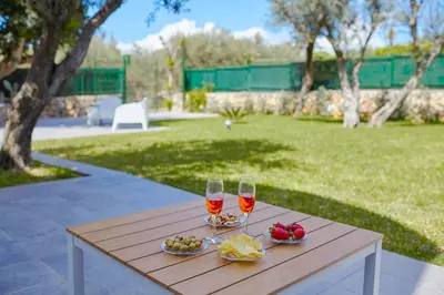 a wooden table with two wine glasses and food on it at Casa del Melograno con idromassaggio e giardino in Terrasini