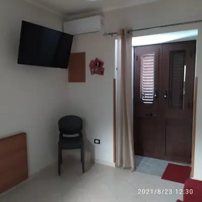 a room with a chair and a television and a door at STONE HOUSE e Casa Vacanze Zia Rosina in Montemaggiore Belsito