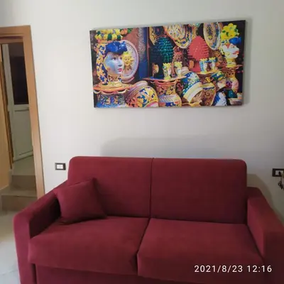 a red couch in a living room with a painting on the wall at STONE HOUSE e Casa Vacanze Zia Rosina in Montemaggiore Belsito