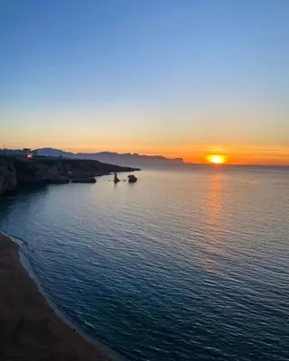 a sunset over the ocean with trees in the foreground at Terra Sinus Holiday House in Terrasini