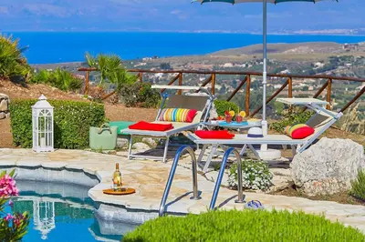 a patio with a table and chairs and an umbrella at Villa Delfino - Scopello-Villas in Scopello