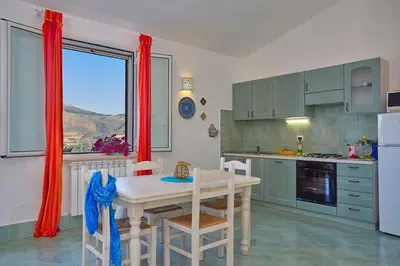 a kitchen with a table and chairs and a window at Villa Delfino - Scopello-Villas in Scopello