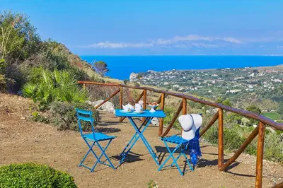 a table and chairs on a balcony with a view of the ocean at Villa Delfino - Scopello-Villas in Scopello