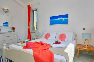 a bedroom with a white bed with red towels on it at Villa Delfino - Scopello-Villas in Scopello