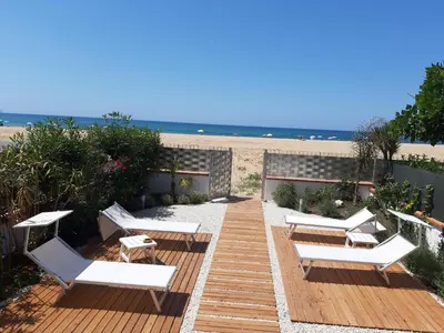 a wooden deck with white lounge chairs on the beach at DORIDE Appartamento sulla spiaggia in Balestrate