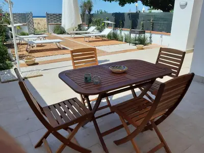 a wooden table and chairs on a patio at DORIDE Appartamento sulla spiaggia in Balestrate