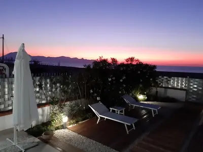 a patio with two chairs and a umbrella and the sunset at DORIDE Appartamento sulla spiaggia in Balestrate