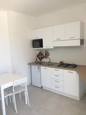 a kitchen with white cabinets and a sink and a table at Alcamo Marina Residence in Alcamo Marina