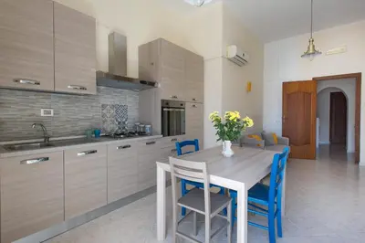 a kitchen with a wooden table and blue chairs at Casetta Vista Mare in Piazza a Mondello by Wonderful Italy in Palermo