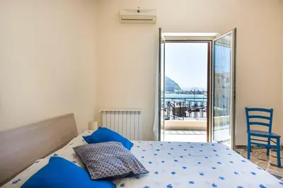 a bedroom with a bed with blue pillows and a balcony at Casetta Vista Mare in Piazza a Mondello by Wonderful Italy in Palermo