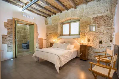 a bedroom with a bed and a stone wall at Stylish Home in Front of Casa Professa by Wonderful Italy in Palermo