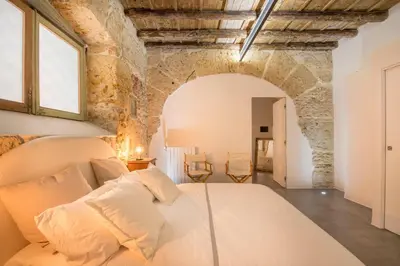 a bedroom with a bed in a room with stone walls at Stylish Home in Front of Casa Professa by Wonderful Italy in Palermo